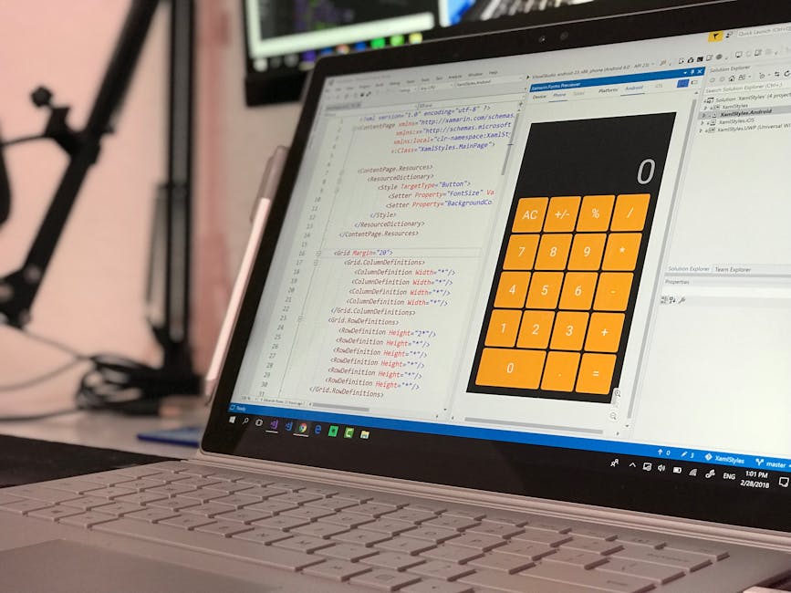 A close-up view of a laptop displaying a coding editor with lines of HTML and CSS code on the left side and a large orange calculator interface on the right side. The calculator features basic functio